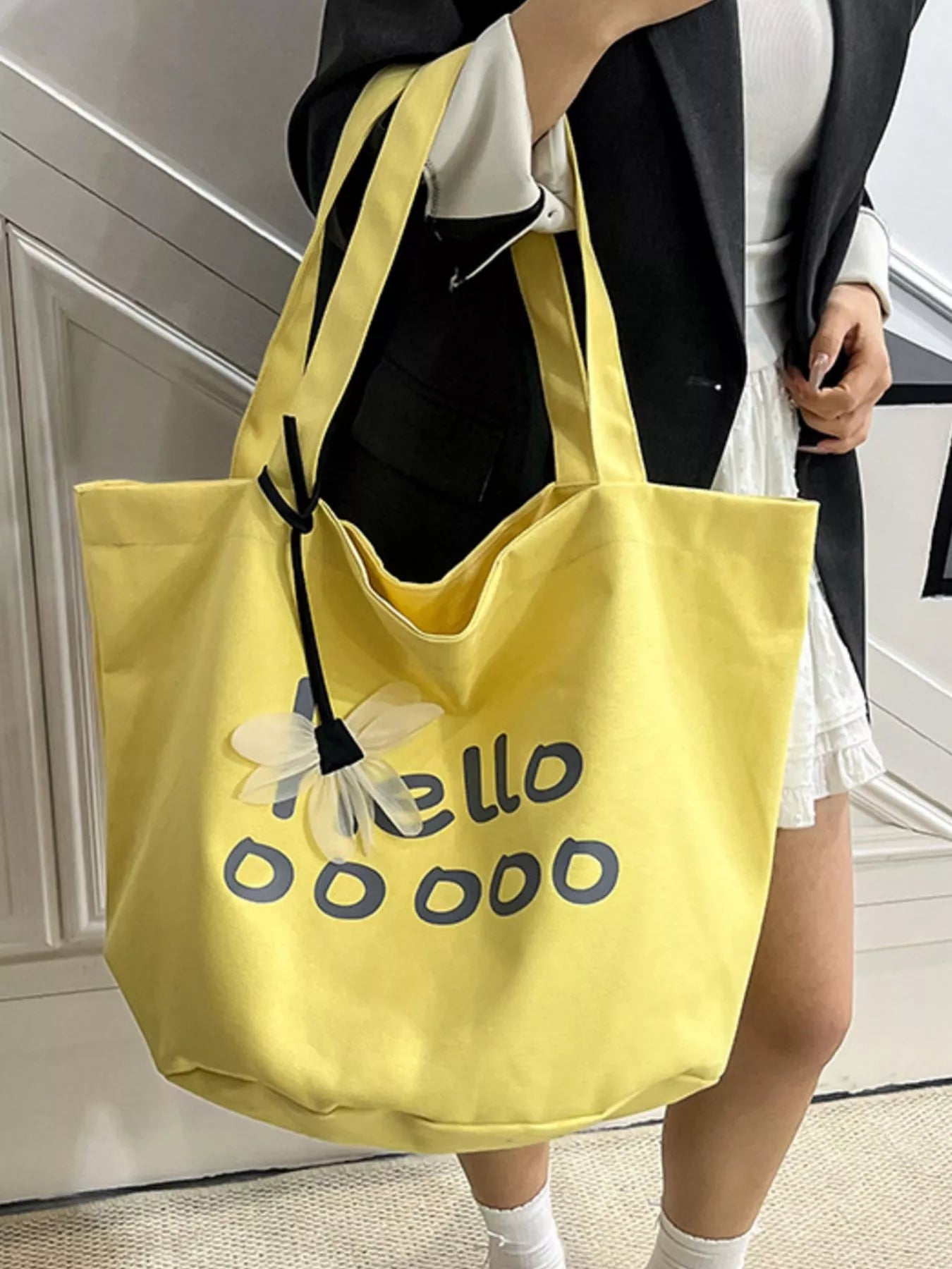 Person holding a yellow tote bag with text and a flower design.