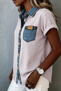 Person wearing a light pink shirt with denim collar and pocket against a gray background