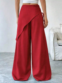 Red wide-leg pants worn by a person in a minimal indoor setting.