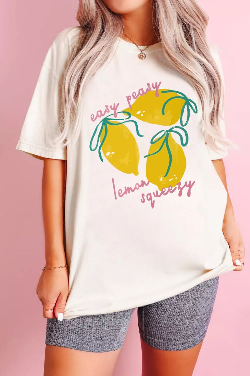 Person wearing a white t-shirt with lemon graphic and text on a pink background