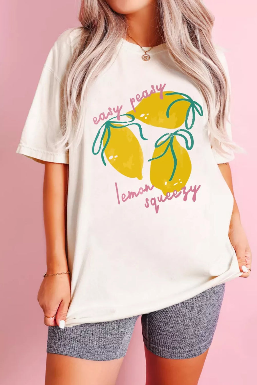 Person wearing a white t-shirt with lemon graphic and text on a pink background