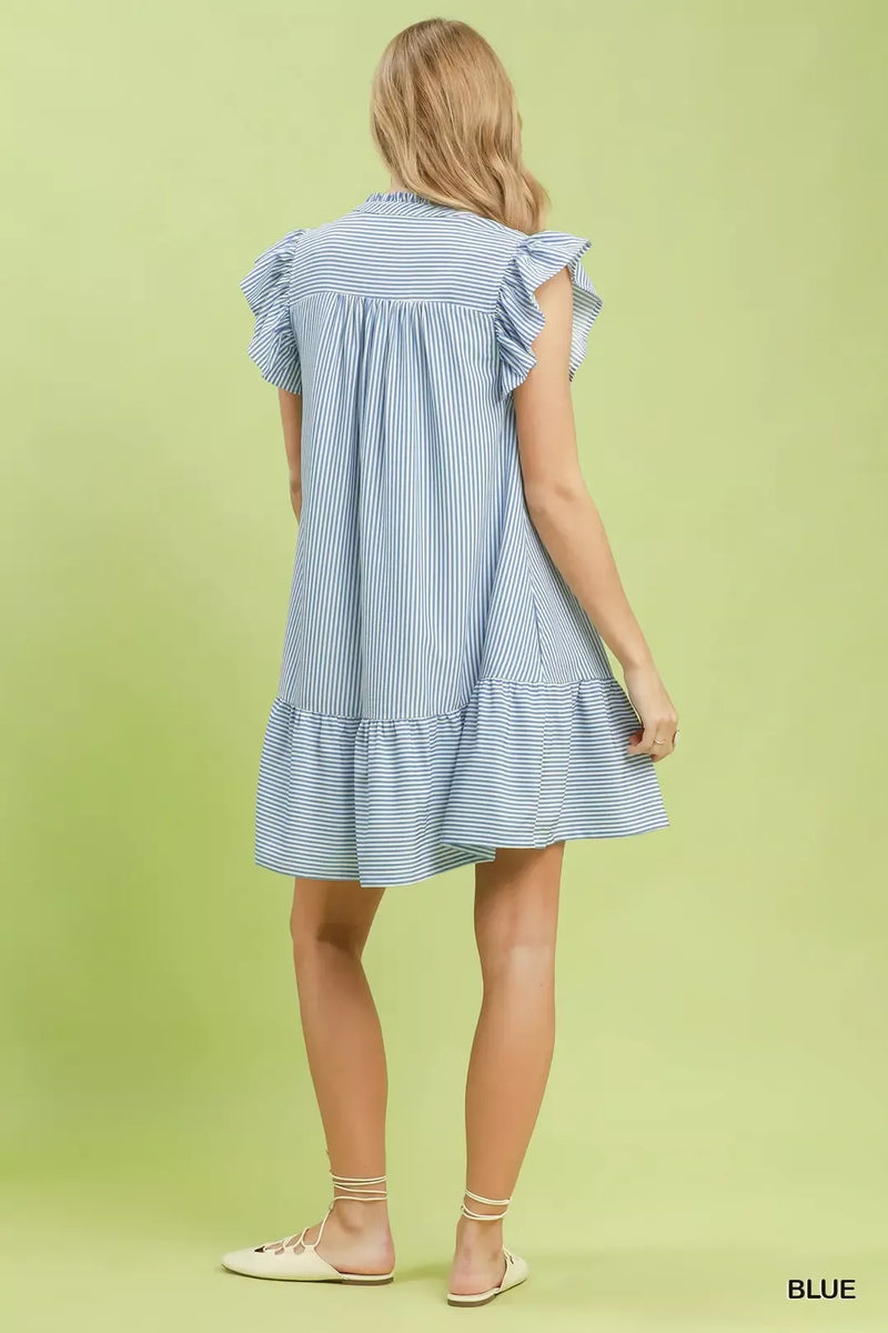 Woman wearing a blue and white striped dress on a light green background