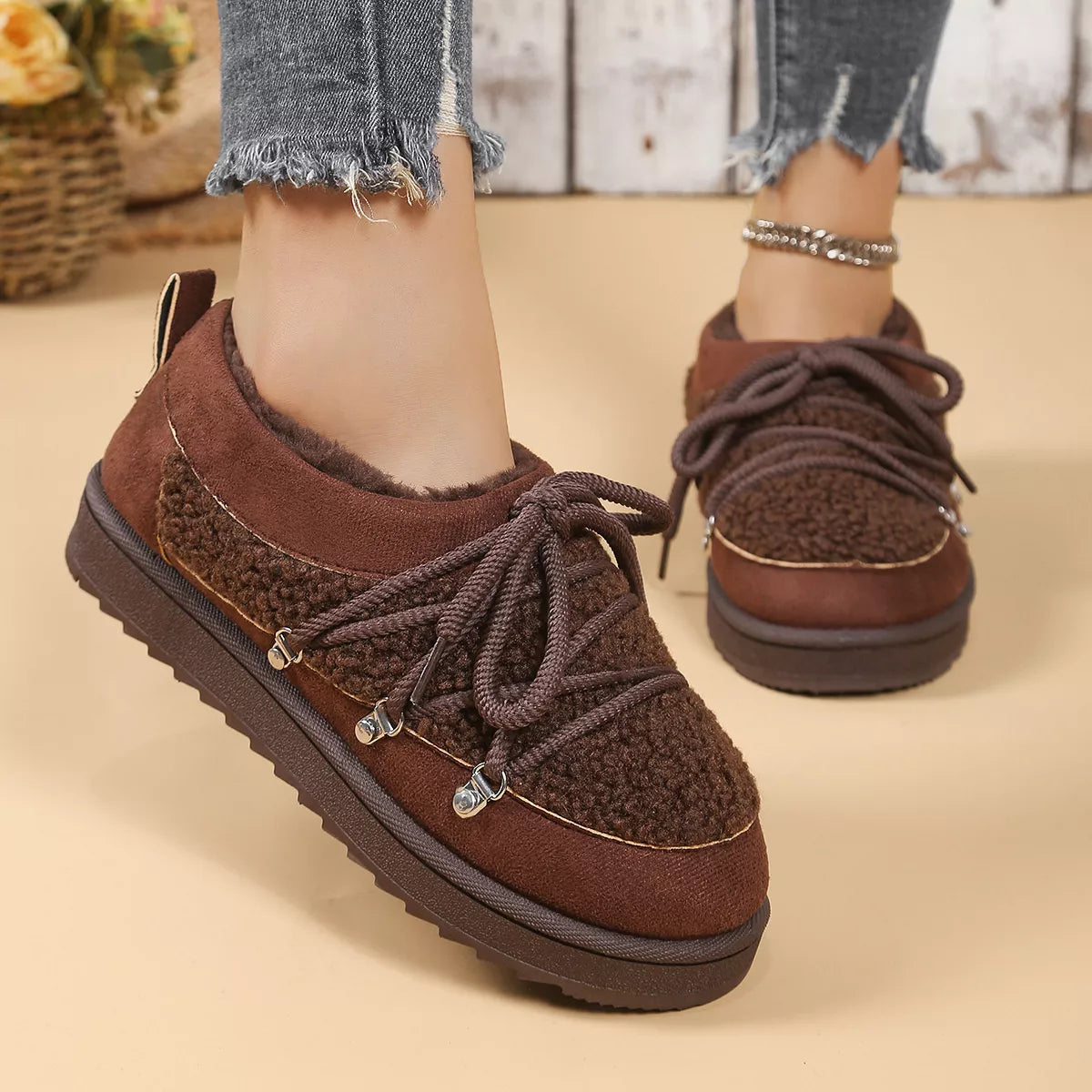 Brown suede shoes with platform sole worn by a person on a beige background