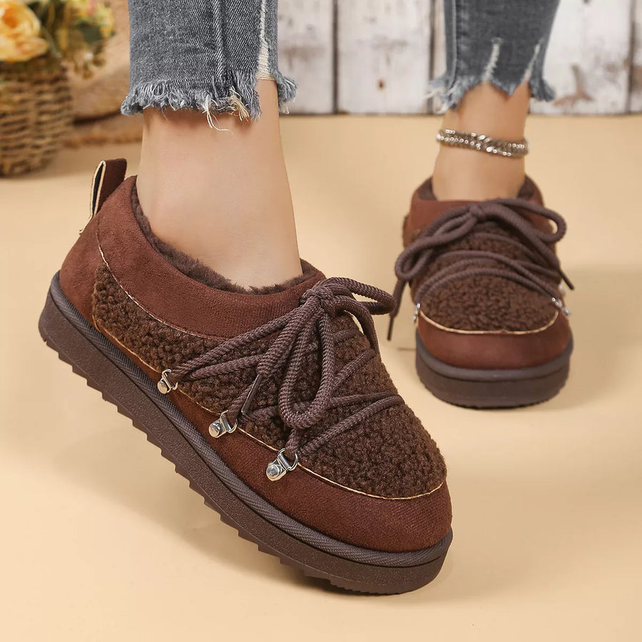 Brown suede shoes with platform sole worn by a person on a beige background