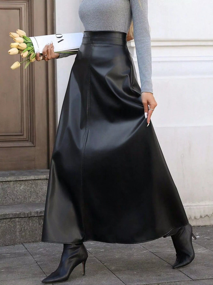 Person wearing a black leather skirt holding yellow tulips against a neutral background