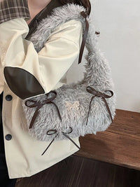 Close-up of a gray fluffy bag with brown drawstrings on a wooden surface.