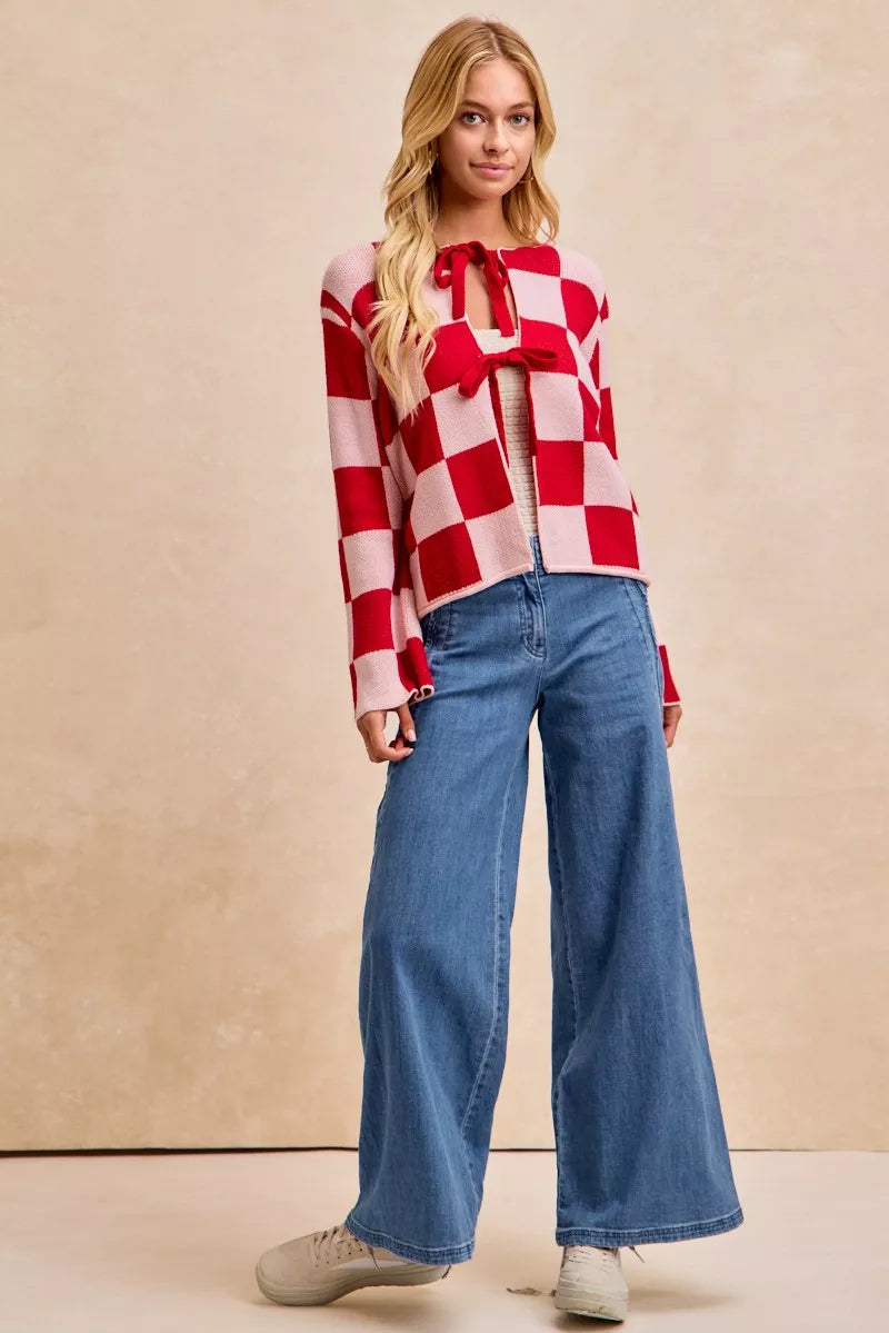 Woman wearing a red and white checkered shirt and blue jeans against a beige background