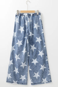 Blue denim pants with white star pattern on a hanger against a white background