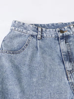 Close-up of a blue denim pocket with stitching details on a light gray background