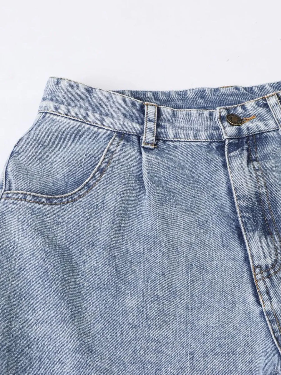 Close-up of a blue denim pocket with stitching details on a light gray background