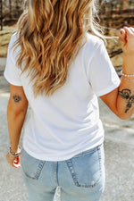 Person wearing a white t-shirt and light blue jeans with tattoos on arms outdoors.