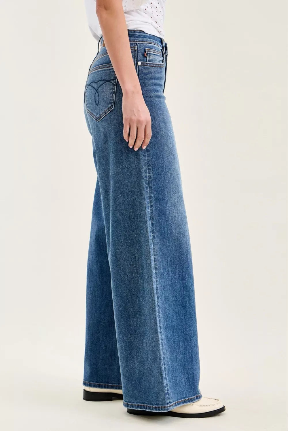 Person wearing blue wide-leg jeans on a white background