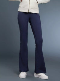 Person wearing navy flared pants and a white jacket on a gray background