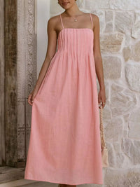 Woman wearing a pink dress standing against a stone wall.