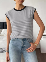 Person wearing a black and white striped shirt and blue jeans indoors.