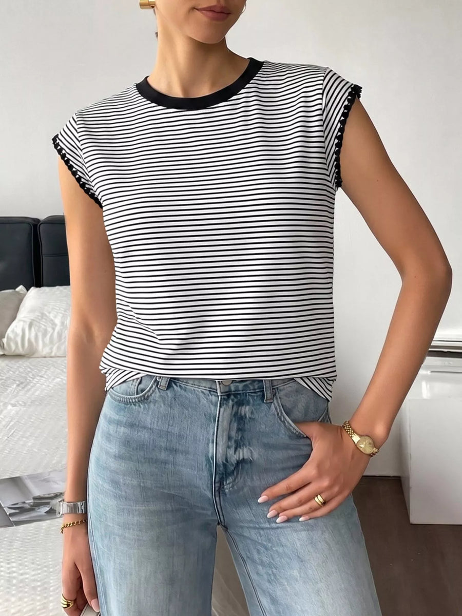 Person wearing a black and white striped shirt and blue jeans indoors.