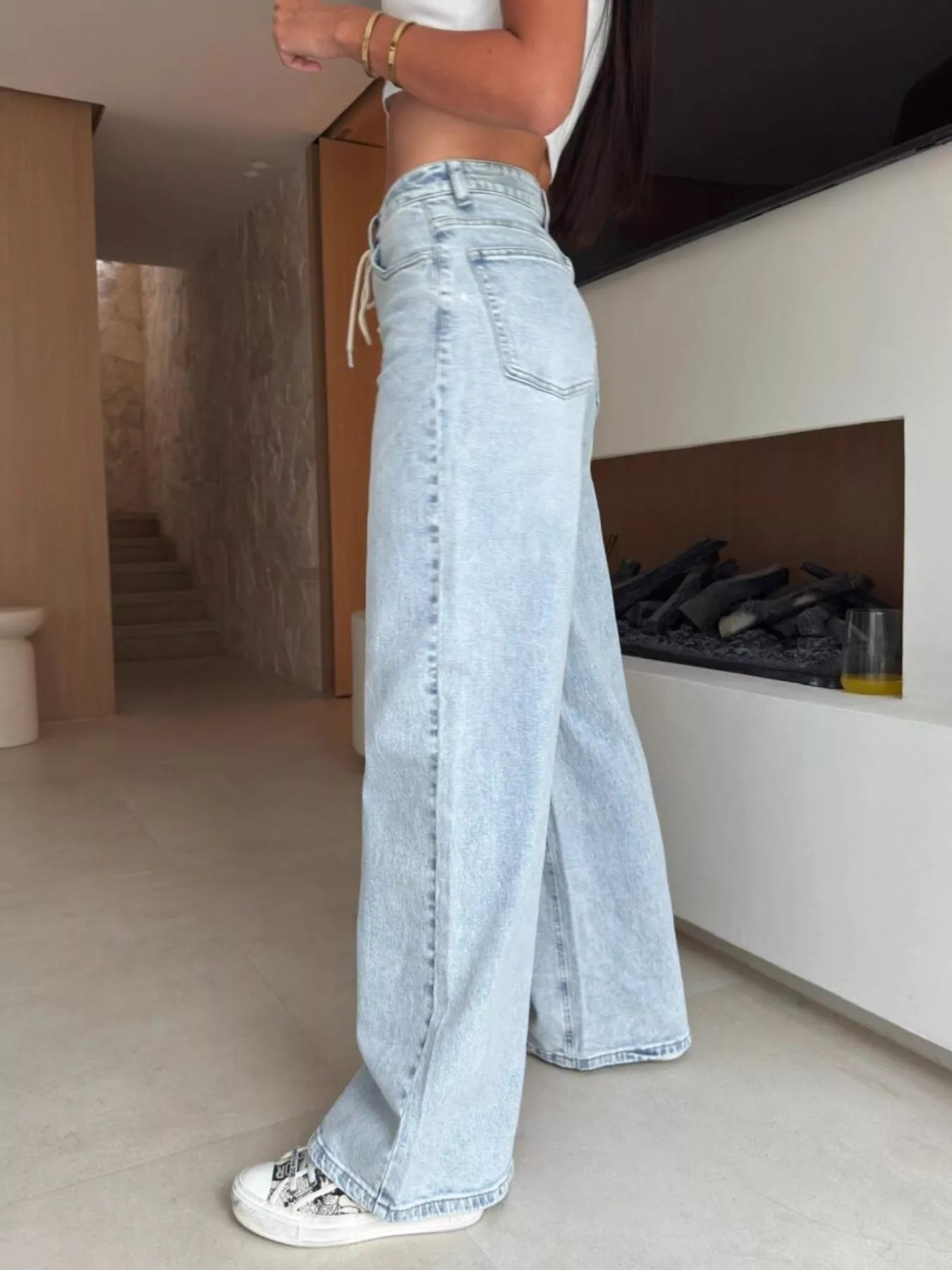 Person wearing light blue jeans in a modern indoor setting