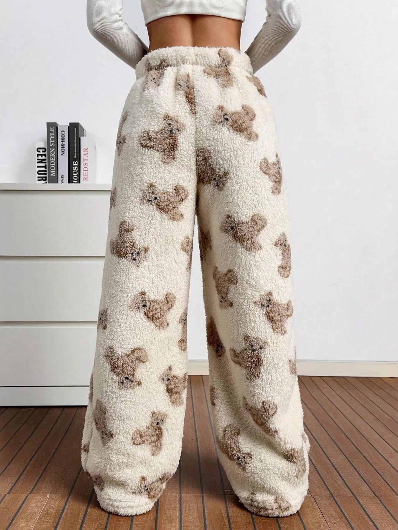 Fluffy pajama pants with teddy bear pattern worn by a person indoors.