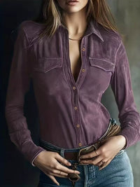 Person wearing a deep purple button-up shirt with a blurred background