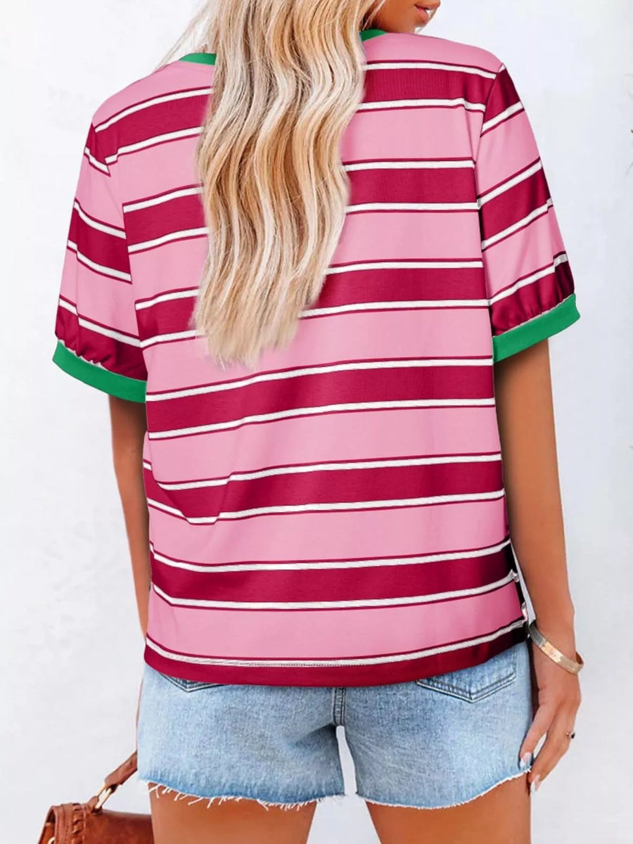 Person wearing a pink and red striped shirt with green trim on a white background