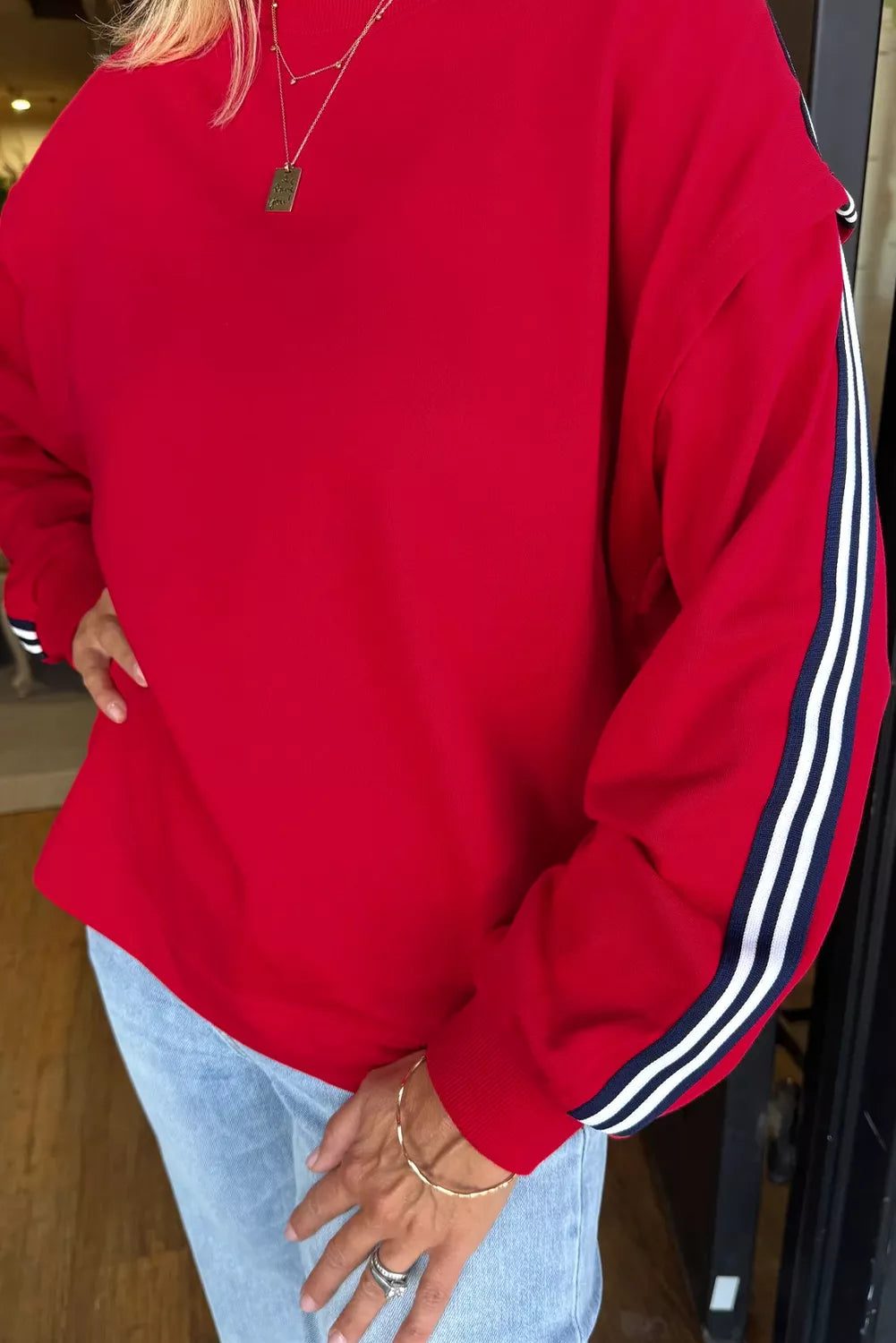 Person wearing a red sweatshirt with white stripes on the sleeves.