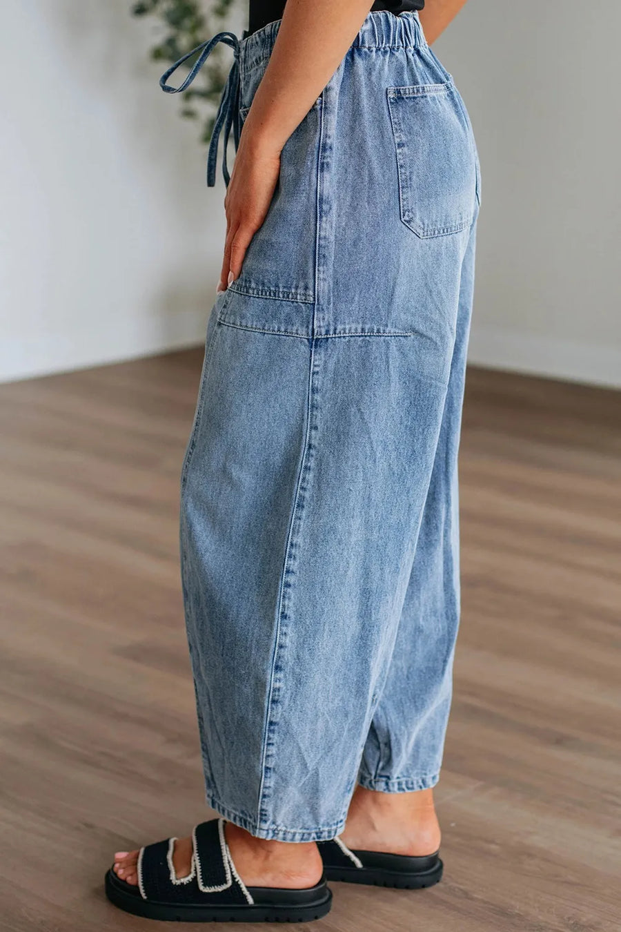 Person wearing light blue denim pants on a wooden floor.