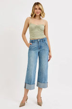 Woman wearing a green tank top and blue jeans on a white background