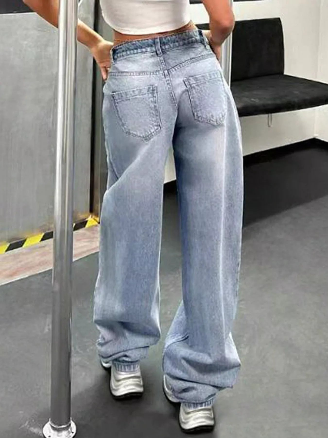Person wearing light blue jeans standing on a subway train.
