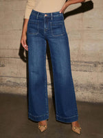 Person wearing blue wide-leg jeans against a textured wall.
