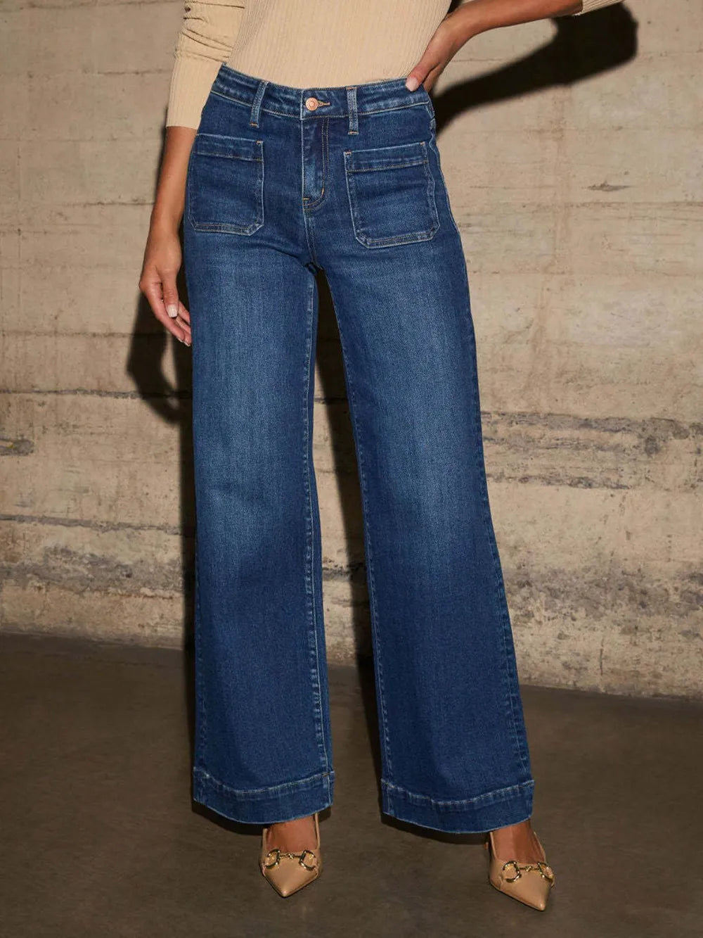 Person wearing blue wide-leg jeans against a textured wall.