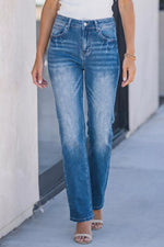 Person wearing blue jeans standing against a light-colored wall.