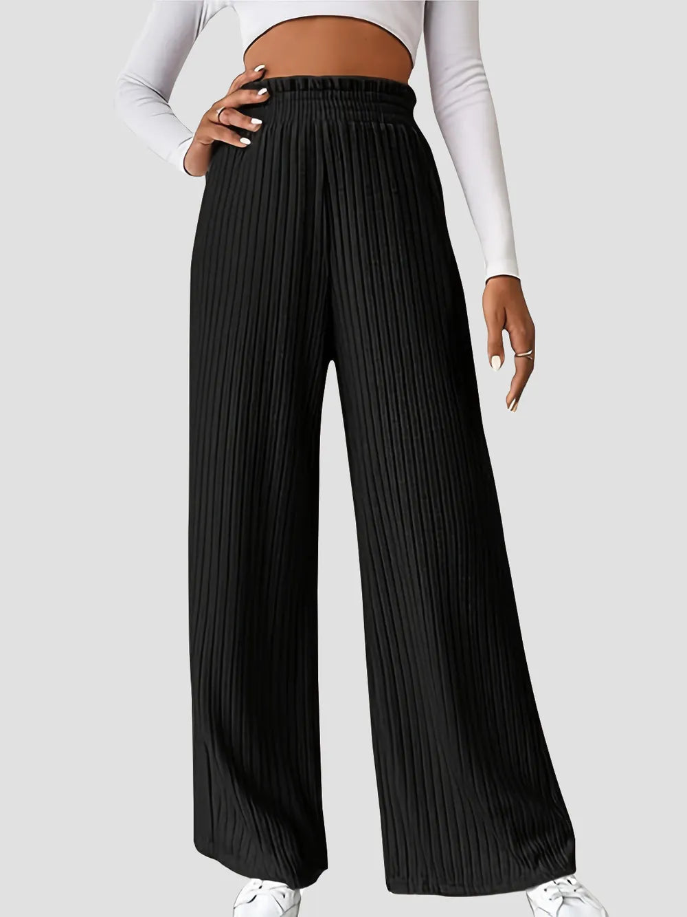 Black pleated wide-leg pants worn by a person on a light gray background