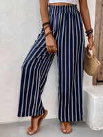 Person wearing navy and white striped pants against a white wall.