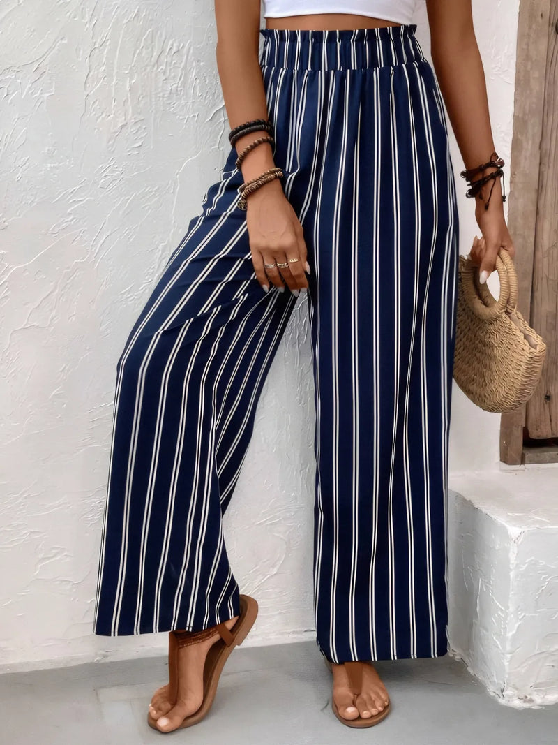 Person wearing navy and white striped pants against a white wall.