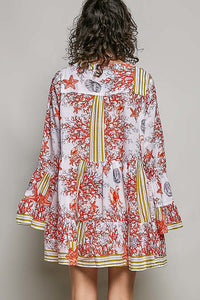 Person wearing a colorful dress with a floral pattern on a plain background