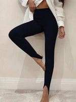 Person wearing black leggings and a white coat against a neutral background