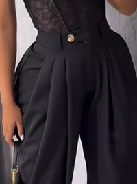 Black outfit with a gold button on a neutral background