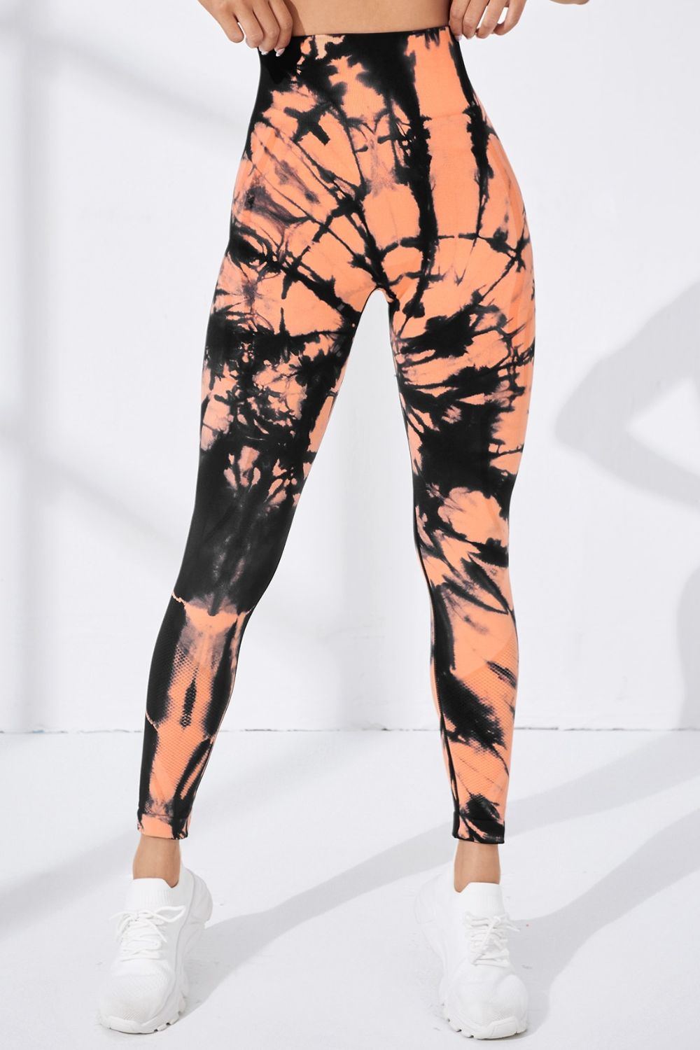 Tie-dye leggings with black and orange pattern on a white background
