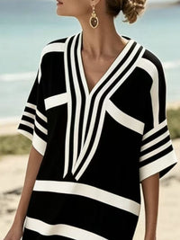 Woman wearing a black and white striped cover-up on a beach.