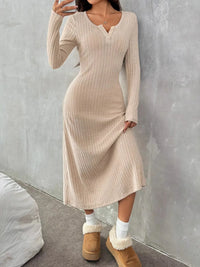 Person wearing a beige ribbed dress with brown boots against a gray wall.