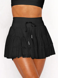 Black tiered skirt worn by a person on a white background