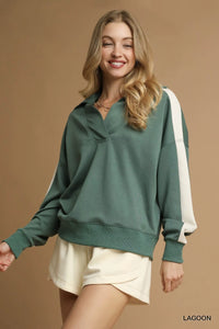 Woman wearing a green sweatshirt with white accents on a beige background