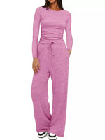 Woman wearing a pink long-sleeve top and pants set on a white background