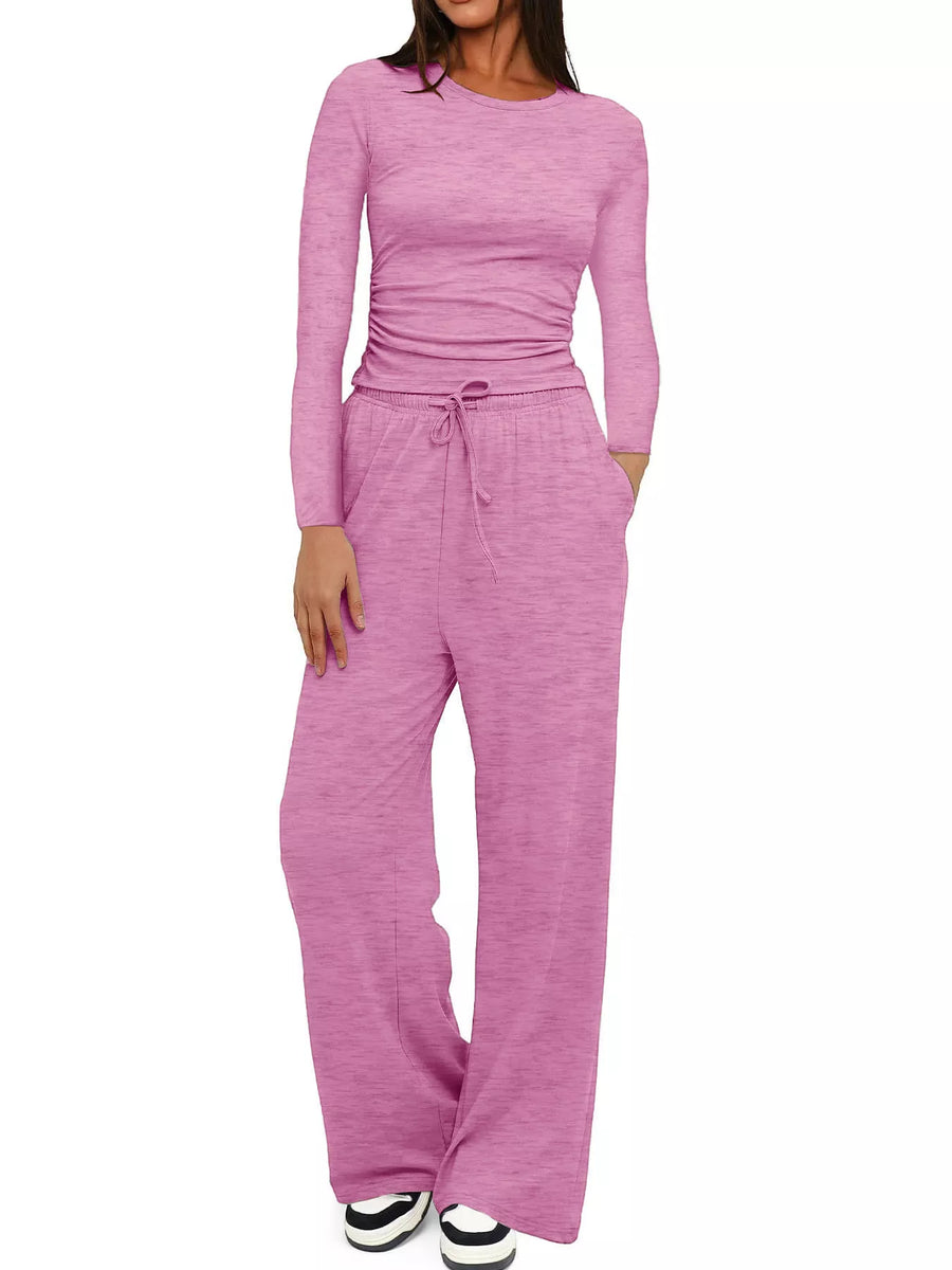 Woman wearing a pink long-sleeve top and pants set on a white background