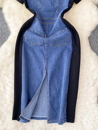 Blue denim dress with black sleeves on a textured white surface