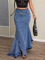 Person wearing a long blue denim skirt with a plain background