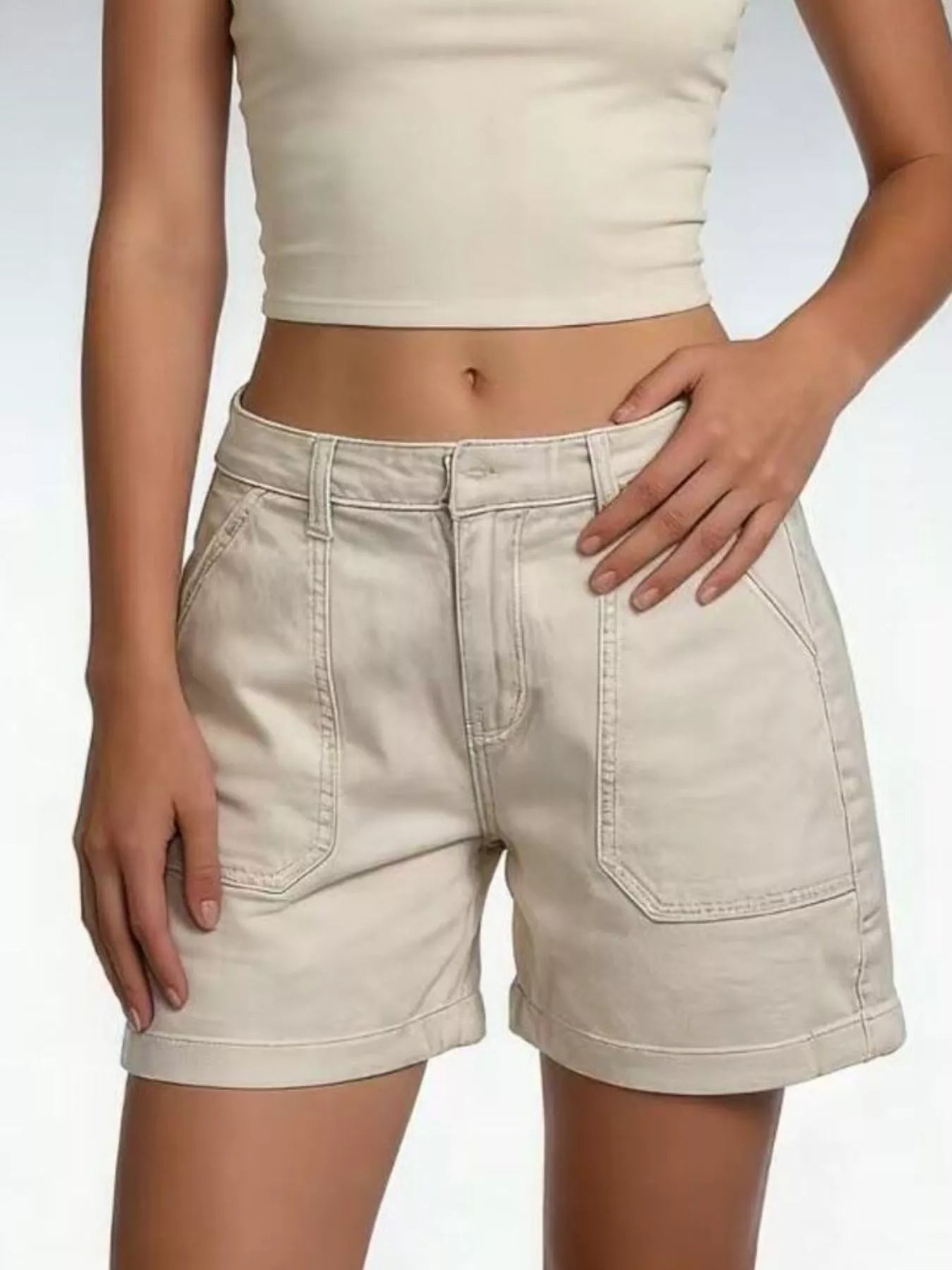 Person wearing beige shorts and a matching top on a plain background