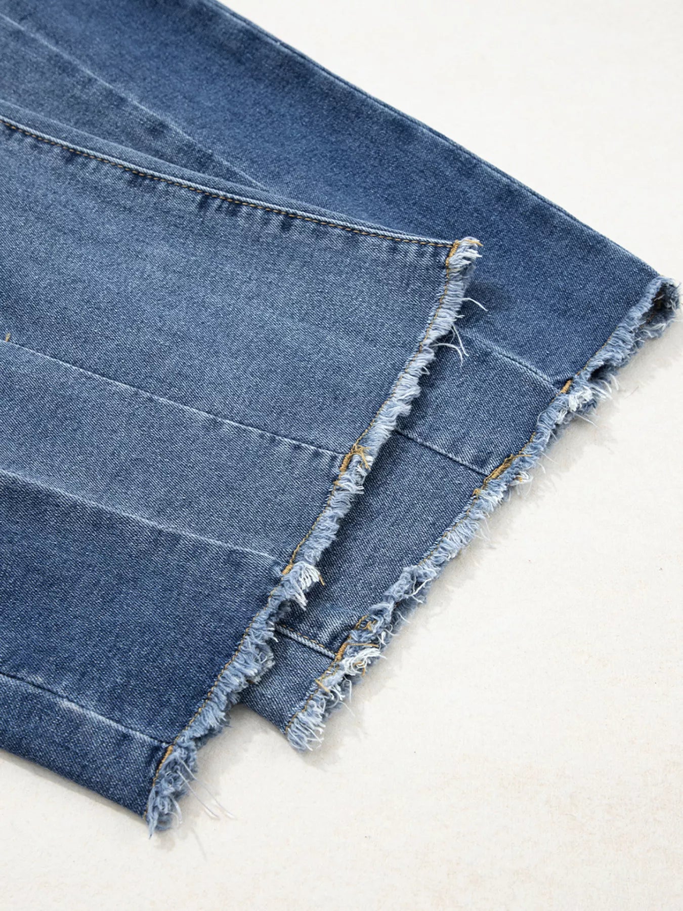Close-up of blue denim fabric with frayed edges on a light background