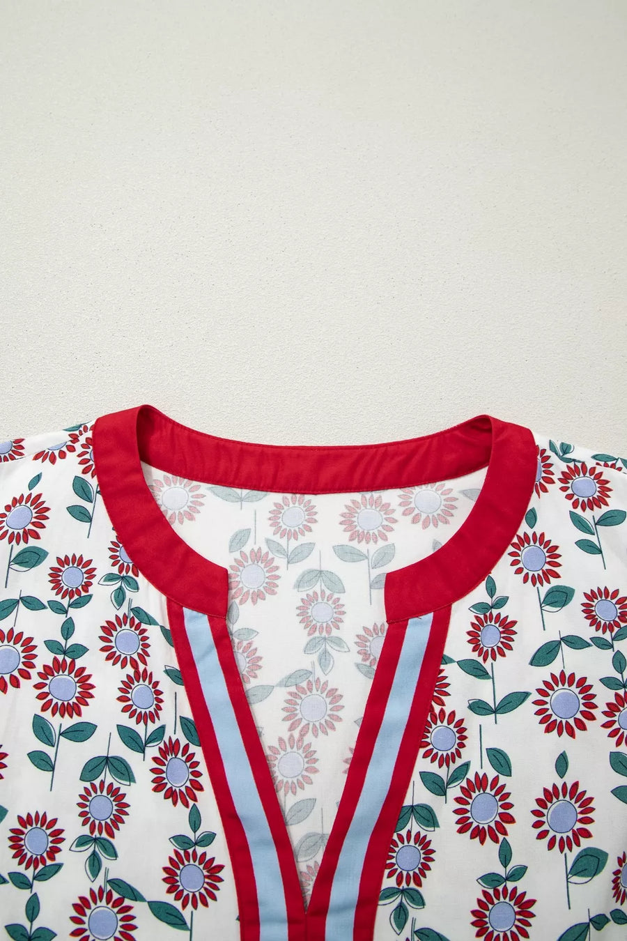 Floral patterned garment with red trim on a plain background