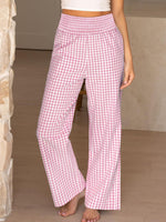 Person wearing pink and white checkered pants in a neutral setting